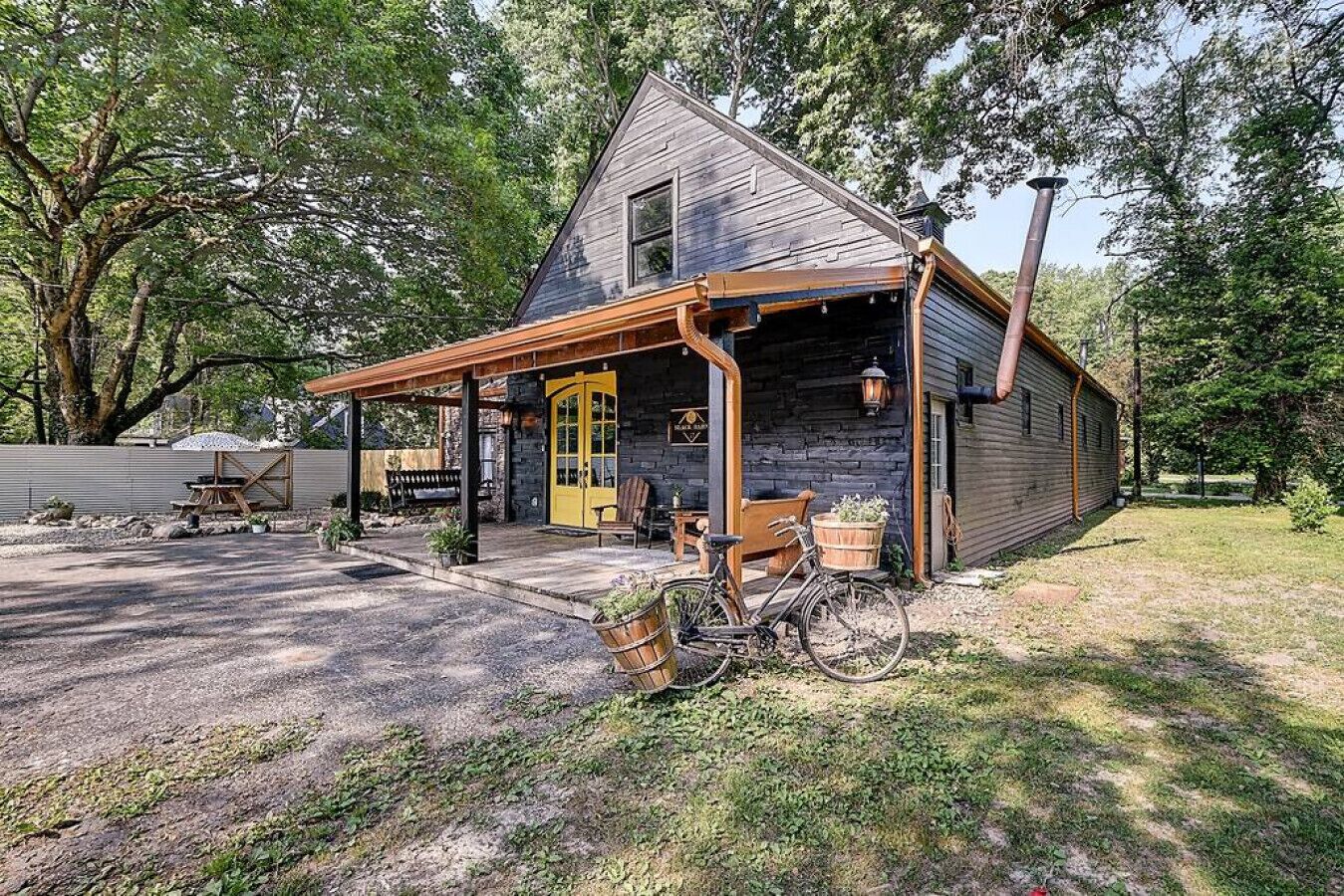 A rustic cabin with a porch, a bicycle, and outdoor seating.