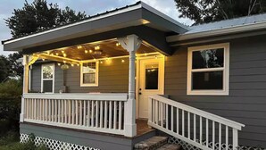 Ein Haus mit Veranda, einem überdachten Bereich mit Lichterketten und einer Haustür.