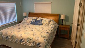 A bedroom with a bed, two bedside tables, a ceiling fan, and a door. - Beachside 1/1 apartment just steps from beautiful Saint Augustine Beach (St. Augustine)