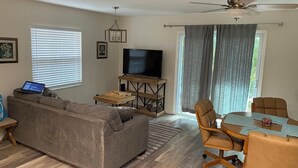 A living room with a sofa, TV, wooden coffee table, and chairs. - Beachside 1/1 apartment just steps from beautiful Saint Augustine Beach (St. Augustine)