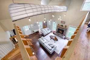 A spacious living room with a large sofa, a fireplace, and a wooden staircase.