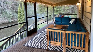 A covered porch with a blue sofa, wooden bench, and a view of a river. - Riverside Oasis! Close to Helen and Wineries (Suches)