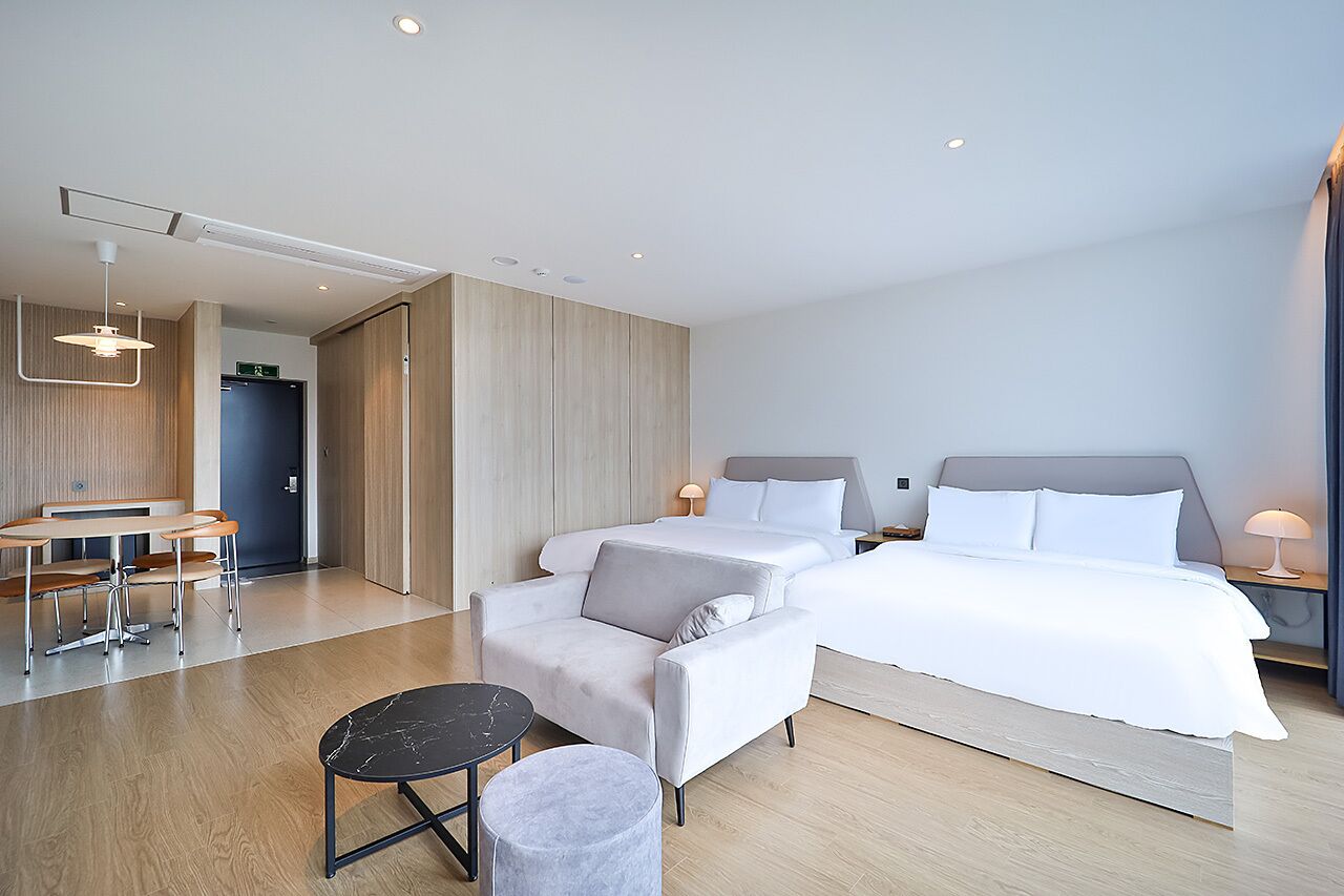 Une chambre d’hôtel moderne avec un grand lit, un bureau avec des chaises, une petite table ronde et un canapé.