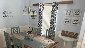 Een eetgedeelte met een rustieke houten tafel, teal stoelen en een decoratieve schaal.