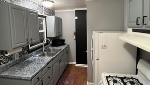 Una cocina compacta con armarios grises, un refrigerador blanco, una estufa y un microondas.