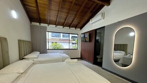 A hotel room with two beds, a large mirror, and a window with a view of buildings.