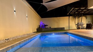A swimming pool with tiled flooring and a surrounding patio area.