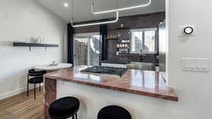 A modern kitchen with a central island, black bar stools, and a white countertop. - Ash & Ko Boutique Lodging (Phoenix)