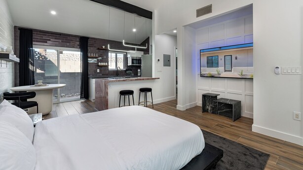A modern hotel room with a large bed, a small dining area, and a kitchen in the background. - Ash & Ko Boutique Lodging (Phoenix)