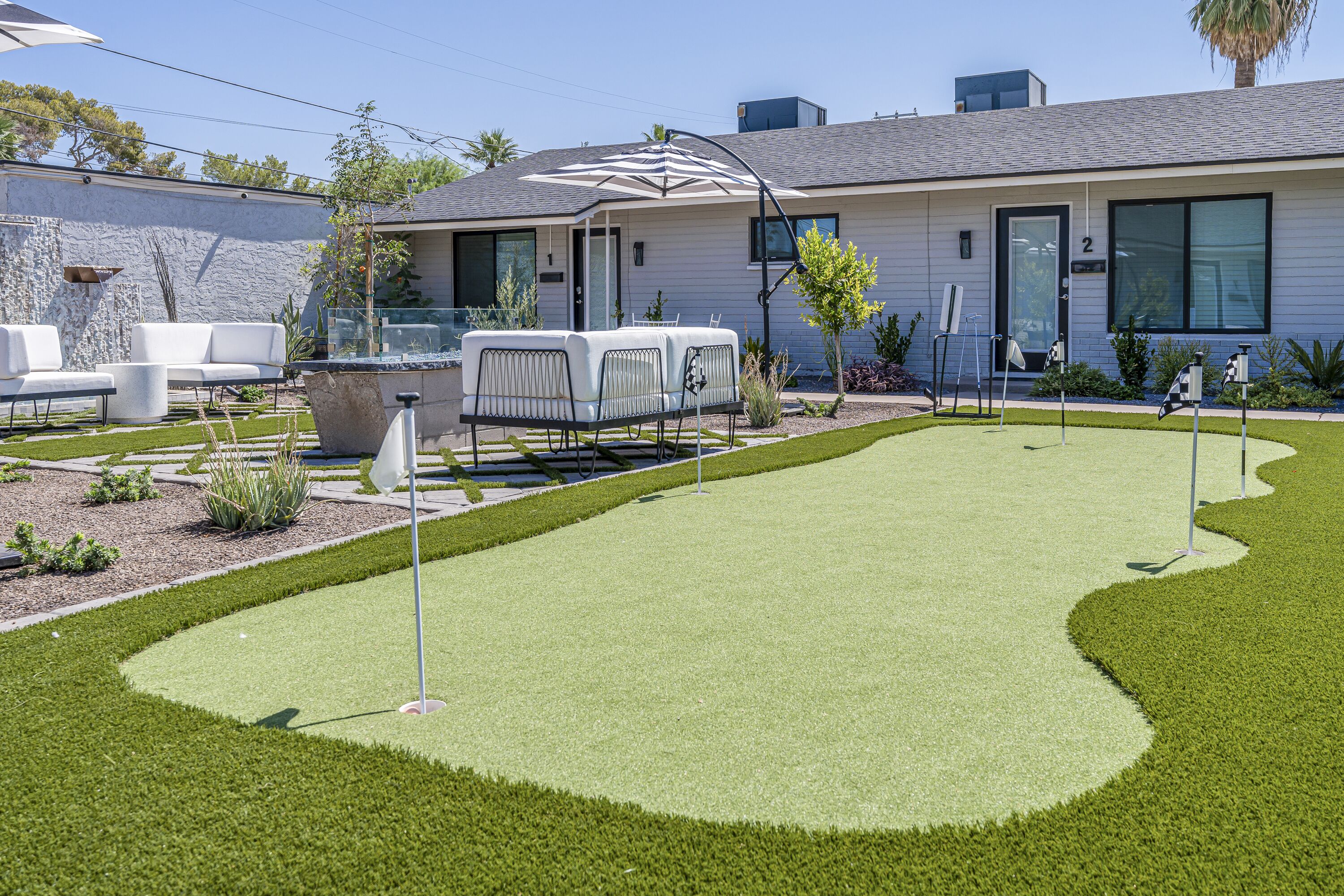 A modern house with a well-maintained lawn, outdoor furniture, and a patio area.