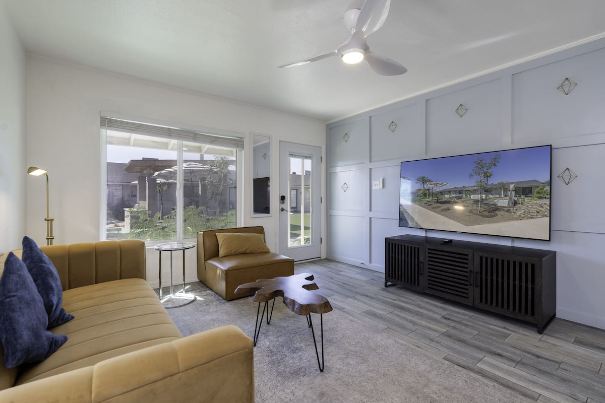 A modern living room with a sofa, a coffee table, and a television on a wall.