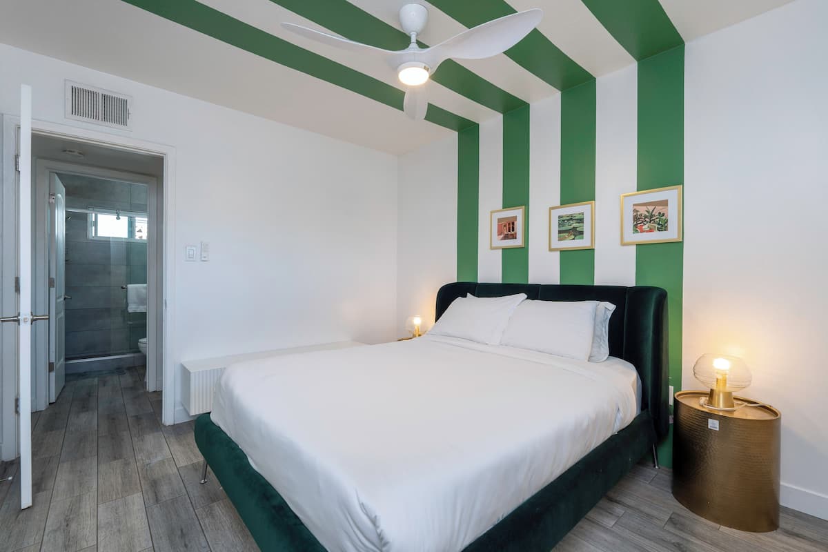 A bedroom with a bed, a ceiling fan, and a bedside table with a lamp.