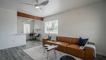 A modern living room with a brown leather sofa, a white coffee table, and a ceiling fan.