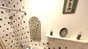 Een badkamer met betegelde vloer, wastafel, toilet en douche.