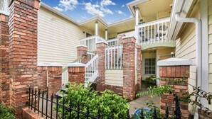 A two-story house with a brick exterior, a white front porch, and a balcony. - Grand Superior Condo 3BD Apartment Disney Parks (Kissimmee)