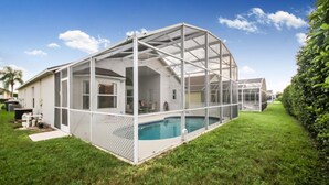 A house with a large glass-enclosed swimming pool, surrounded by a white fence and a well-maintained lawn. - Grand Luxury 4BD Pool Home Disney Universal (Davenport)