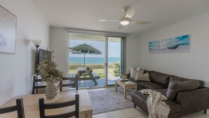 A living room with a view of the sea, a ceiling fan, and a dining area with a table and chairs. - Craigmore 5 - Oceanfront Escape with Yamba's Best Beach Views - Holiday Yamba (Yamba)