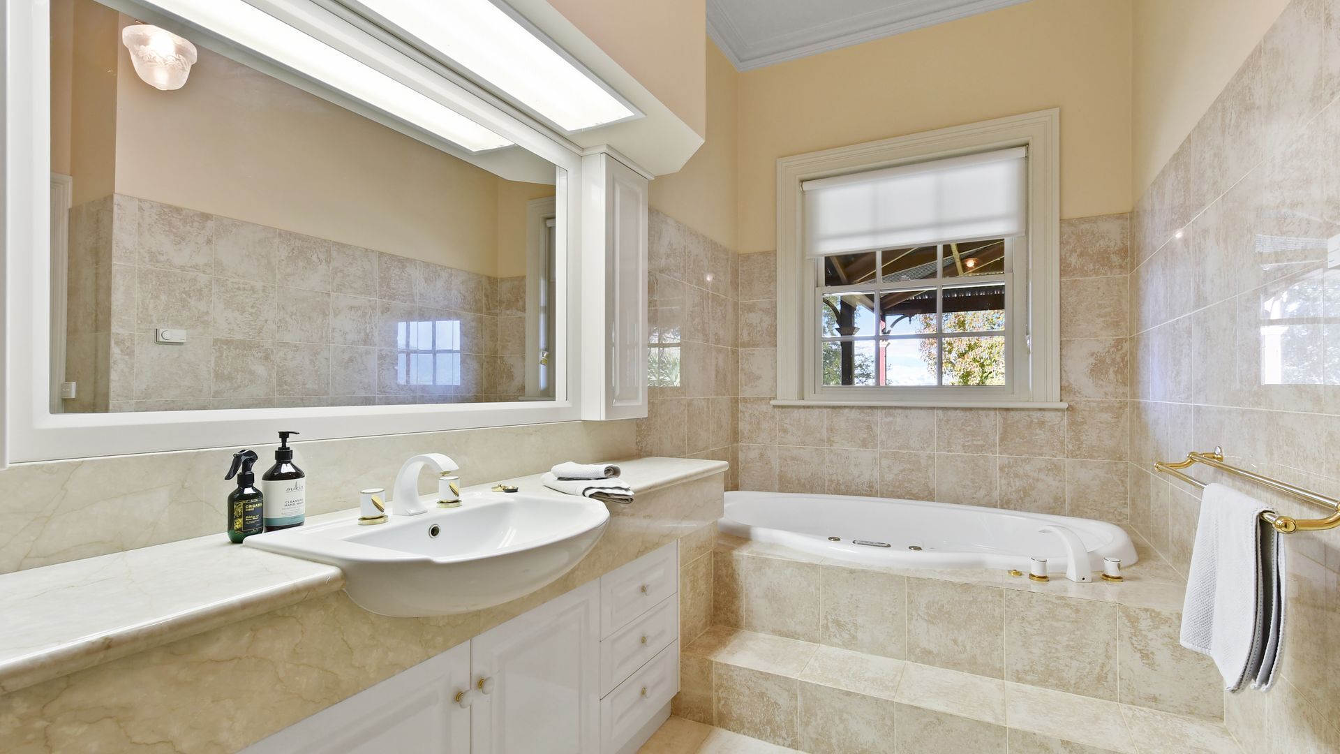 Un bagno con uno specchio grande, due lavandini, una vasca e una finestra.
