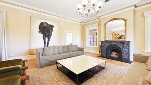 A spacious living room with a fireplace, a large painting of a horse, and a chandelier. - Cornhill - Merrijig - Sleeps 12 (Merrijig)