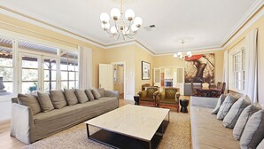 A spacious living room with a large sofa, a coffee table, and a dining area with chairs. - Cornhill - Merrijig - Sleeps 12 (Merrijig)