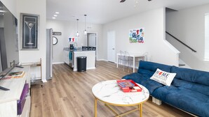 Una sala de estar moderna con un sofá azul, una mesa de centro redonda y un ventilador de techo.