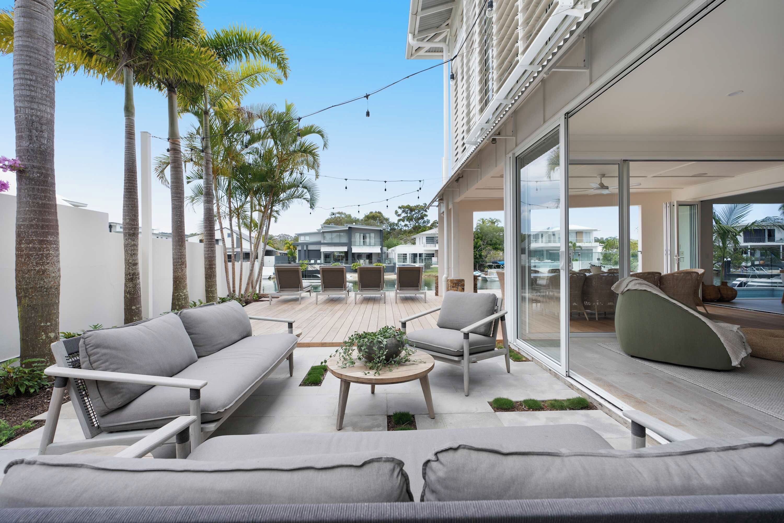 A modern outdoor living area with a pool, lounge chairs, and a view of neighboring houses.