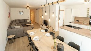 Een moderne keuken met een eethoek, een zithoek met een bank en een televisie.
