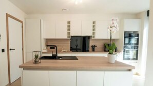 Een moderne keuken met witte kasten, een houten aanrechtblad, een zwarte spoelbak en een potorkidee.