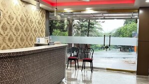 Zona de recepción con pared estampada, mostrador, dos sillas y vistas al exterior.