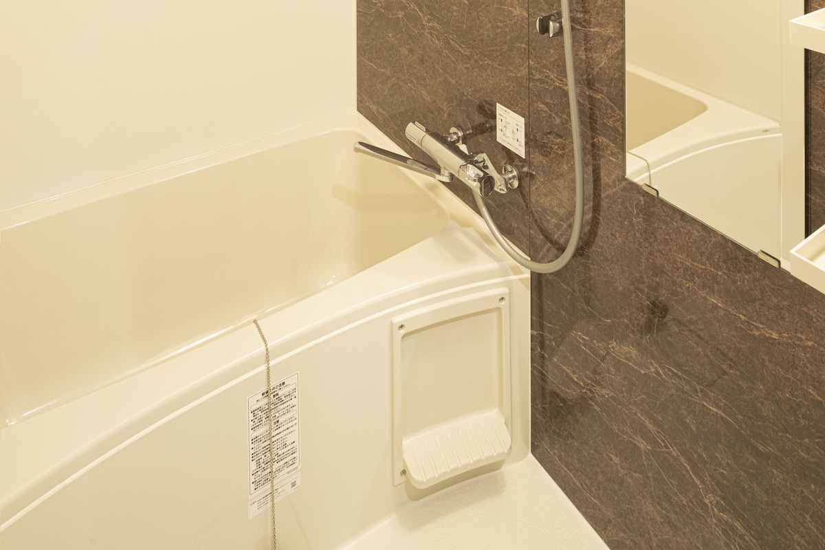 A modern bathroom with a bathtub, a shower, and a mirror.