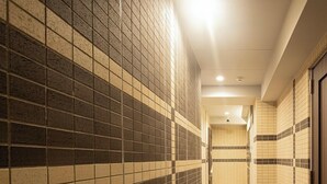 A corridor with tiled walls and floor, leading to a door at the end. - Coruscant Hotel Nagasaki Station 3 (Nagasaki)