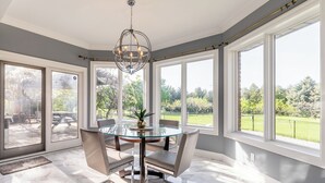 A dining area with a glass table, chairs, and a chandelier.