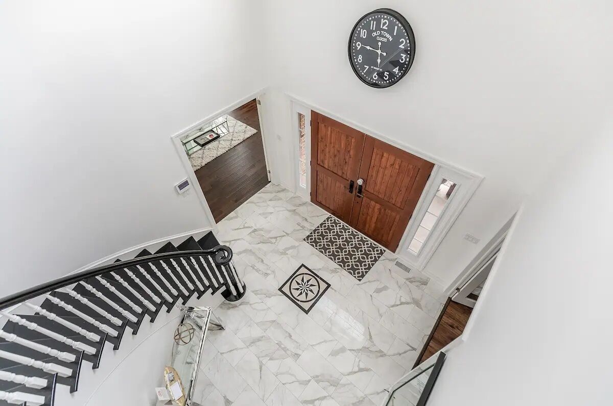 Um interior moderno com uma escada em espiral, uma porta de madeira e um relógio na parede.