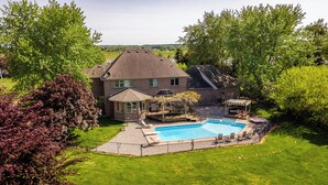A house with a backyard swimming pool, a covered patio, and a fenced yard.