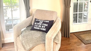 Une pièce chaleureuse avec une grande horloge murale, un fauteuil confortable et une vue par la fenêtre.