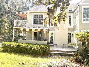 Uma casa de dois andares com varanda coberta e um espaço de estar ao ar livre.