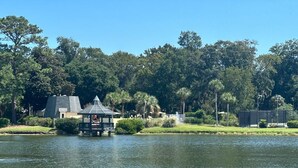 Une vue sur le lac, avec un belvédère, une maison et des arbres denses en arrière-plan.