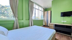 Een hotelkamer met een bed, een televisie en een raam met gordijnen.
