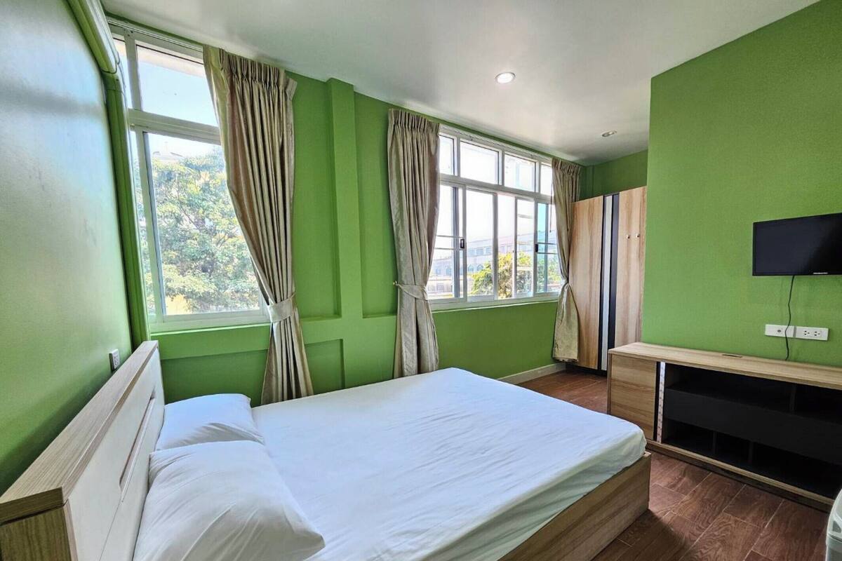 Een kamer met een bed, een televisie en een raam met gordijnen.