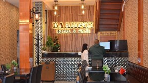 Een receptiegedeelte met een 'BAMPHE HOTEL & CAFE' bord, een receptiebalie en zitplaatsen.