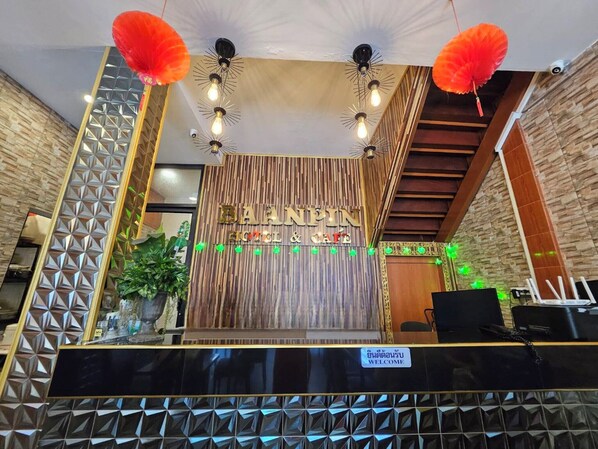 A reception area with a wooden wall, a black reception desk, and red hanging decorations.