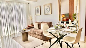A modern living room with a glass dining table, beige sofa, and a large mirror.