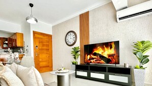A modern living room with a flat-screen TV, wooden cabinets, a round coffee table, and a sofa.