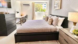 A modern bedroom with a large bed, a desk, and a chair.