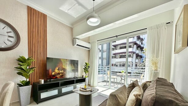 A modern living room with a flat-screen TV, a sofa, a coffee table, and a potted plant.