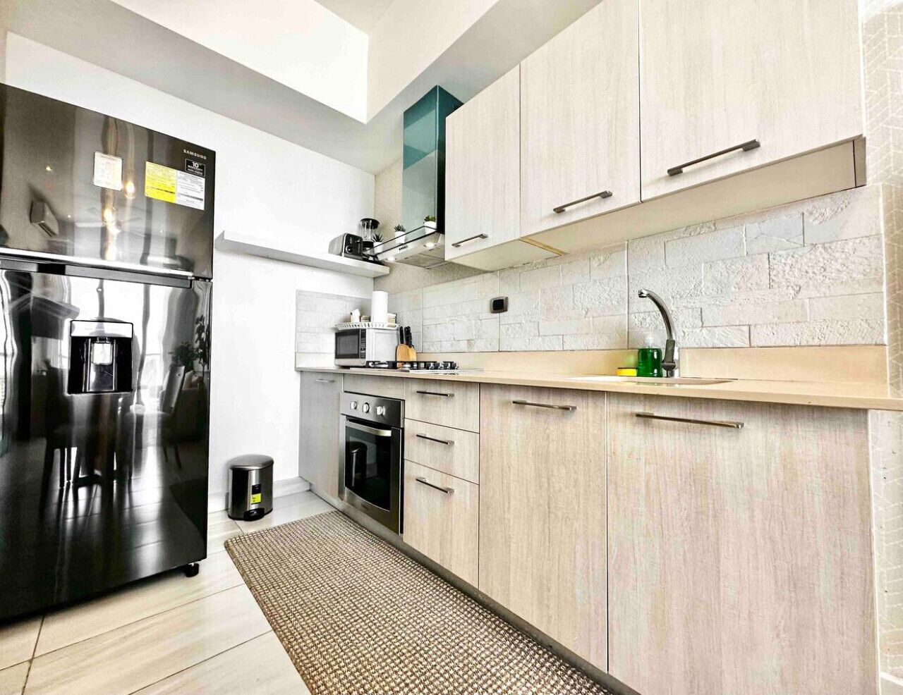 Una cocina moderna con un refrigerador de acero inoxidable, un microondas y un horno empotrado.