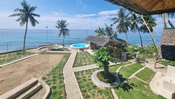 Un resort con piscina, palmeras y vista al océano.