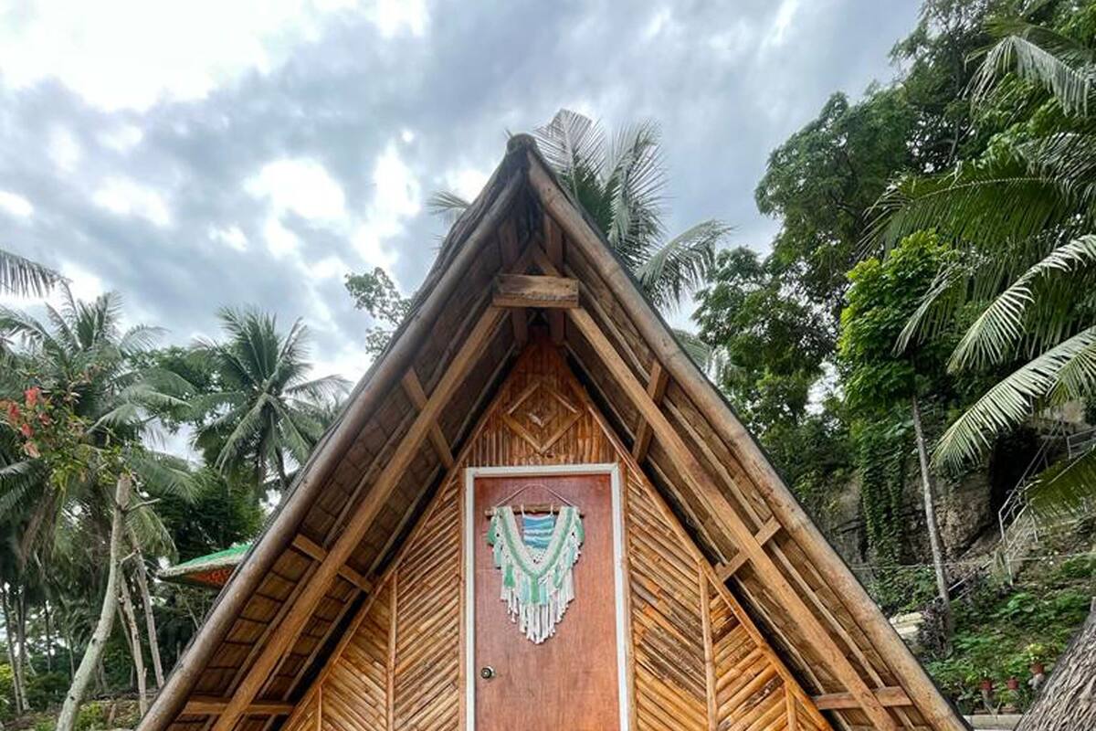 Une hutte au toit de chaume, dotée d’une porte en bois et d’une décoration suspendue.