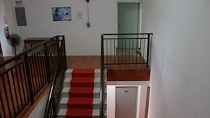 A staircase with red carpet, a fire extinguisher, and a door marked 202. - Lucky Home Hotel and Apartment (Tinian)