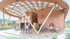 Una estructura moderna de madera con un diseño de techo único, zonas de estar y un letrero visible que indica que es una casa de huéspedes.